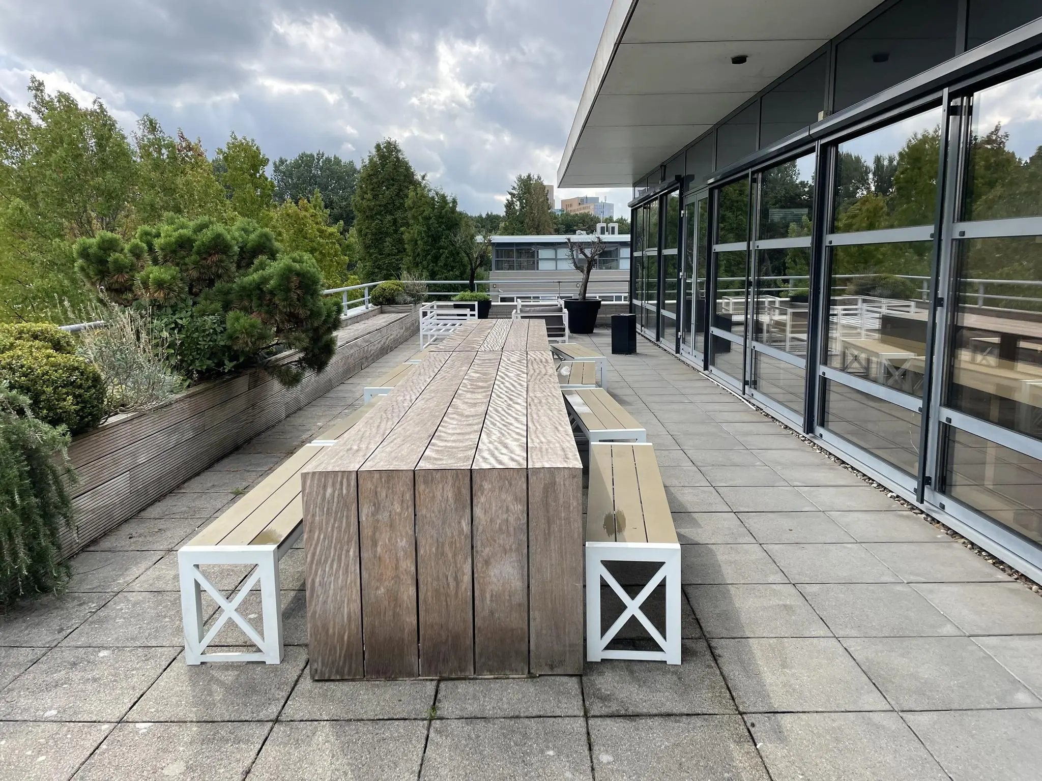 Dakterras aan de Jan Leentvaarlaan met houten picknicktafels, banken en beplanting langs de rand.